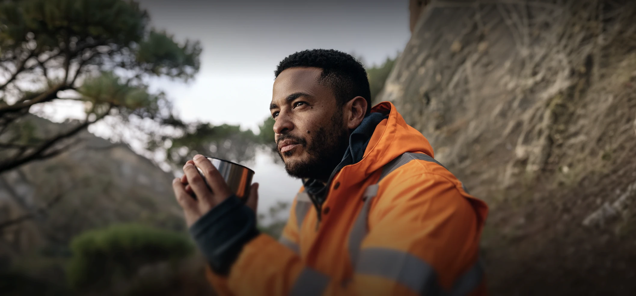 Environmental field worker in orange PPE beside a river
